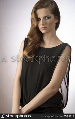very pretty young girl with charming expression, stylish make-up and long hair wearing sexy elegant black dress