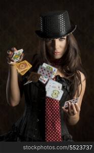 very sexy brunette female wearing sexy burlesque dress, playing with poker cards and looking in camera with sensual expression