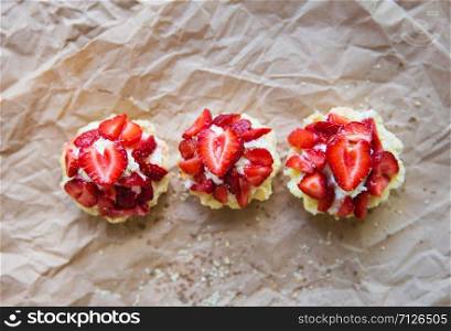 Very tasty muffins with fresh strawberries lie on kraft paper.. Very tasty muffins with fresh strawberries lie on kraft paper