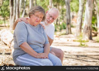 Very Upset Senior Woman Sits With Concerned Husband Outdoors.