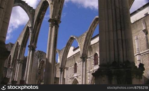 Verzierte Rundb?gen / Tore aus Stein einer alten Kathedrale; im Hintergrund das GebSude der Kathedrale; wei?e Wolken ziehen am blauen Himmel.