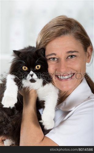 Veterinary hugging a cat and reassuring for review