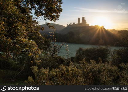 Vibrant sunrise over medieval castle ruins with fog in rural landscape