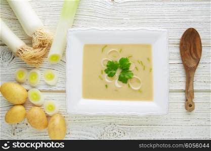 vichyssoise cream soup with leeks and potatoes on white wood table
