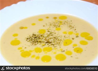 Vichyssoise soup with olive oil spills and parsley in white plate.