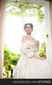 Victorian beautiful woman, white dress at home window with plants