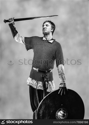 Victorious medieval knight armor with a sword and shield, black and white image