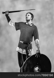 Victorious medieval knight armor with a sword and shield, black and white image