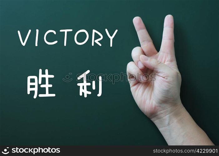 Victory gesture on a blackboard background, with the word victory written in both English and Chinese