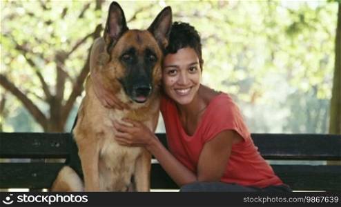 15 of 15 Young people and pet, portrait of a happy Hispanic girl at work as a dog sitter with an Alsatian dog in the park, smiling and looking at the camera