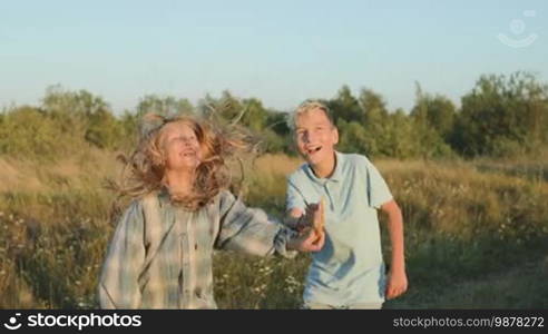 A boy and a girl have launched a kite into the sky and are watching joyfully