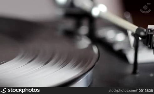 A hand places the tonearm of a record player above a record and lets it come down to the disc