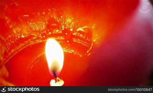A large red burning candle is encircled, the flame is focused in macro form. The wax looks liquid and has strong reflections. Suitable for both romantic or holiday themes - due to the intensity but also for tension and thriller themes.