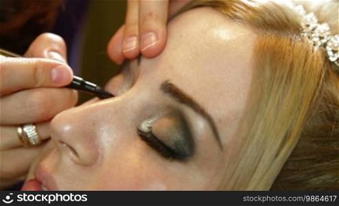 A makeup artist applies makeup to an attractive young woman
