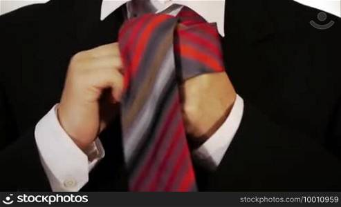 A man ties his tie around his neck and makes a knot