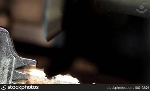 A shiny key is clamped into a grinding machine and finely ground
