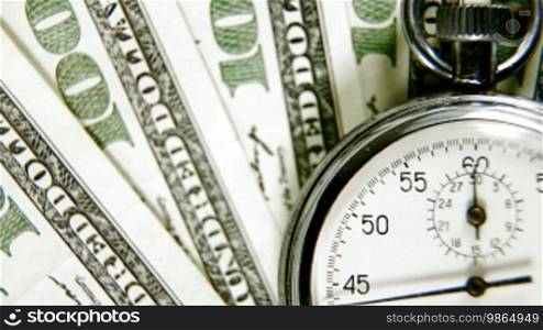 A stopwatch on a background of American dollars