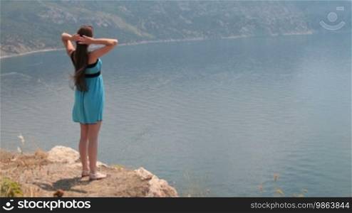 A young woman standing on a rock by the sea in Balaklava, Crimea