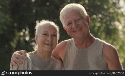 Active retired people, portrait of happy senior husband and wife after fitness and jogging in city park