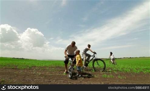 Active young family enjoying bike ride in the country, wide shot