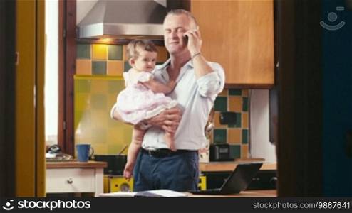 Adult people and child, fatherhood and childbearing, multitasking businessman feeding daughter, working and talking on mobile phone in kitchen at home. Part 2 of 4