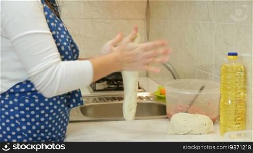 Adult woman kneading stiff dough in the kitchen