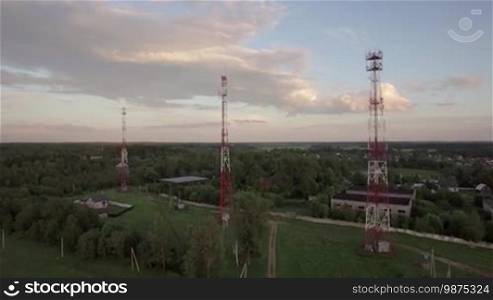 Aerial flight above the countryside in Russia. View of forest, country houses and base stations against blue sky with clouds in daylight at summer