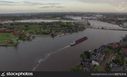 Aerial flight above the Koog Zaandijk, Netherlands. View of river, small countryside houses, dock, factory and fields