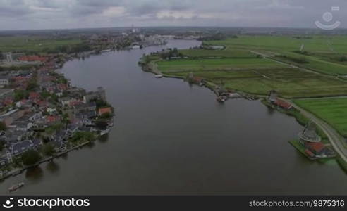 Aerial flight above the Koog Zaandijk, Netherlands. View of town on the one side of river and agricultural fields on the other side