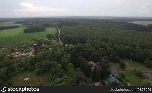 Aerial flight above the Lukino, Domodedovsky District, Moscow, picturesque landscape of green forest and fields, countryside buildings and traffic