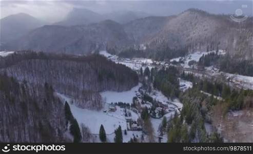 Aerial footage of a small village in the mountains in winter.