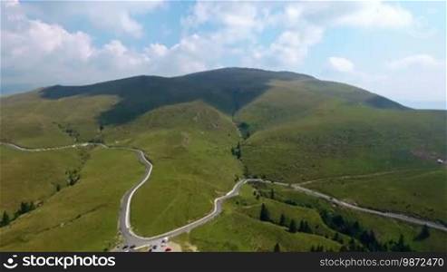 Aerial footage of high altitude mountain road in summer day with cloudy blue sky. Tourism and travelling concept.