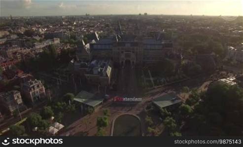 Aerial panorama of Dutch capital with view to Rijksmuseum, Art Square with pond and I amsterdam slogan. Cityscape at sunset