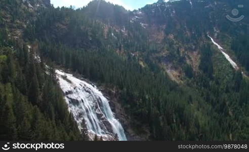 Aerial panoramic view of a waterfall on the pine forests and with sunlight in the mountains in Austria