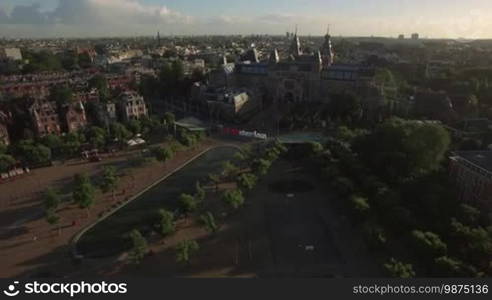 Aerial - Rijksmuseum and Art Square with I amsterdam slogan and pond. Cityscape of Dutch capital at sunset