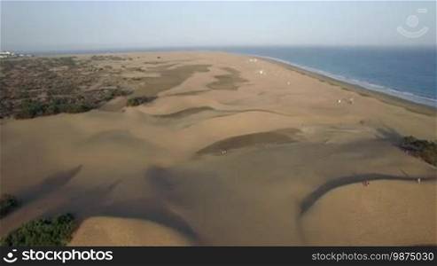 Aerial scene of the coast on Gran Canaria. Beach, blue ocean and vast sandy landscape with dunes