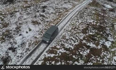 Aerial shot of a car in the frozen snowy countryside