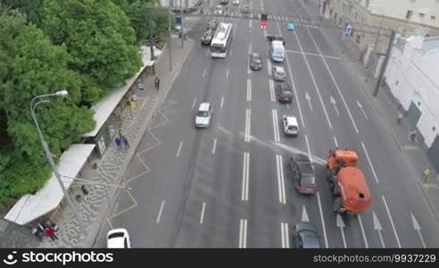 Aerial shot of city highway with cars, public transport stop and vehicle washing the road. Logos unidentified