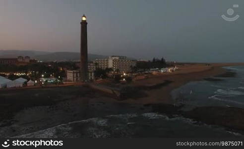 Aerial shot of Maspalomas Lighthouse with light in the dusk. Gran Canaria coast, Canary Islands