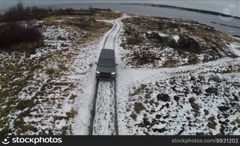 Aerial shot of minivan moving away from the waterside. Winter traveling in Rabocheostrovsk in Karelia, Russia