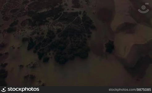 Aerial shot of picturesque sandy landscape with dunes and ocean at sunset, Gran Canaria