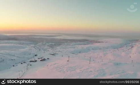 Aerial shot of sunrise in Khibiny mountains in Russia, there is a ski resort at the bottom