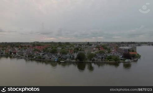 Aerial shot of village houses on the riverside, Netherlands. Scenic waterfront view