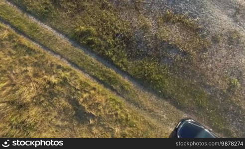 Aerial top view of running girl out from car at the grass next to rocks