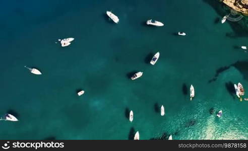 Aerial top view of sailing boat and yachts parked at the wild harbor near the coast in Spain, Catalonia