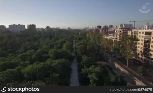 Aerial - Valencia view with green park and car traffic on the road with buildings alongside, Spain