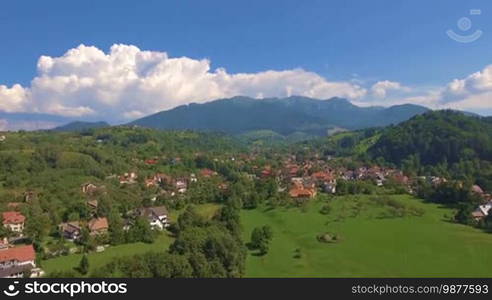 Aerial view from above over small village in mountains. Beautiful landscape in summer day.