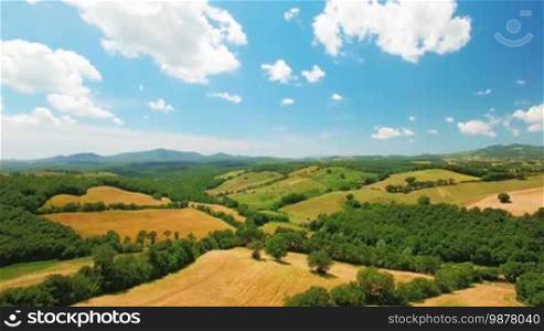 Aerial view of agricultural fields on a summer cloudy day in Italy, Tuscany. In the background, beautiful scenic nature