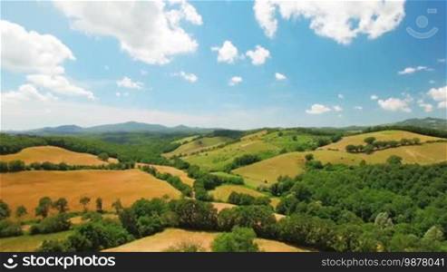 Aerial view of agricultural fields on a summer cloudy day in Italy, Tuscany. In the background, beautiful scenic nature