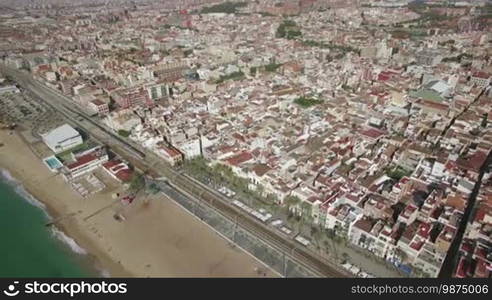 Aerial view of Barcelona coastline and sea, Spain. Beach separated from the city with railway, train moving there